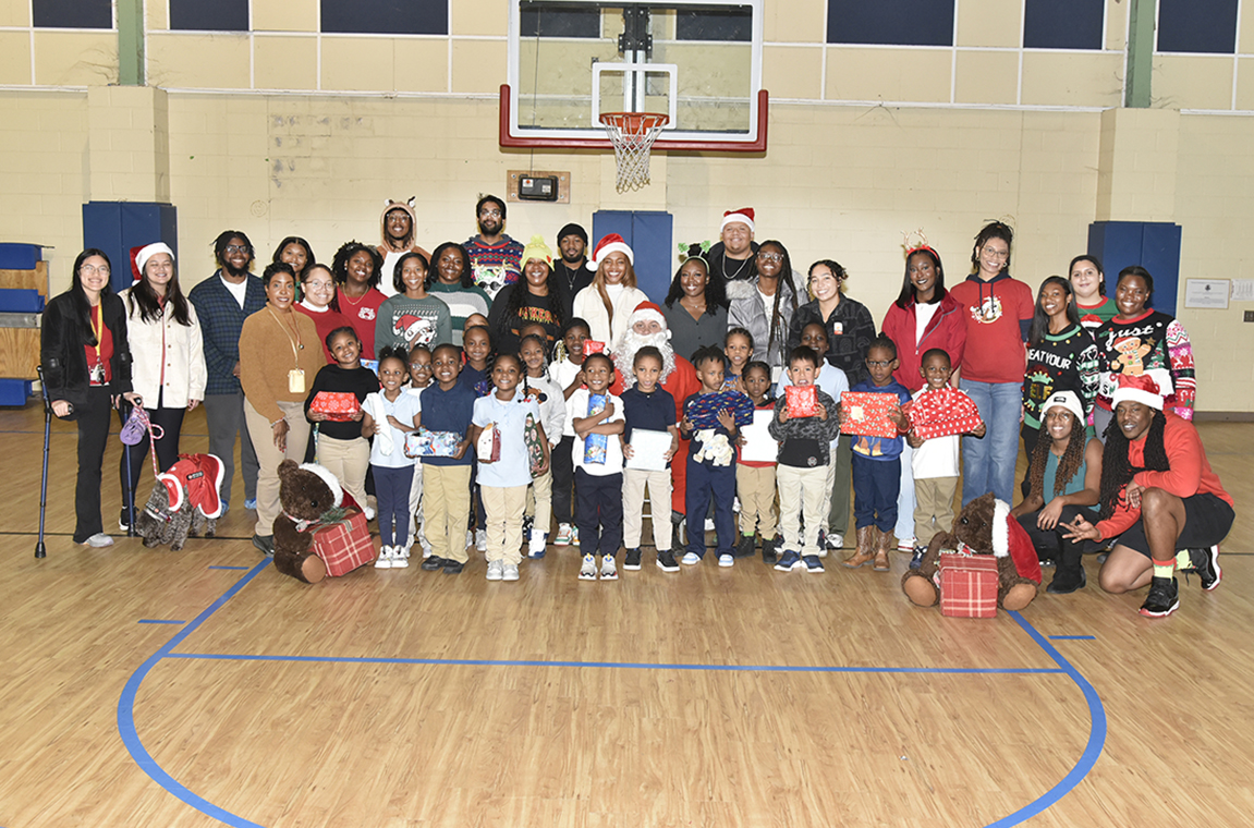 First grade elementary school students pose with Santa and Vet Med students in gym