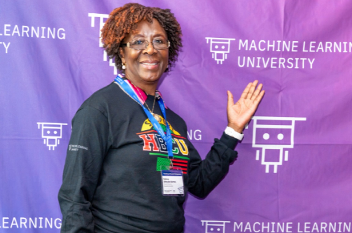 A presenter standing in front of MLU step and repeat