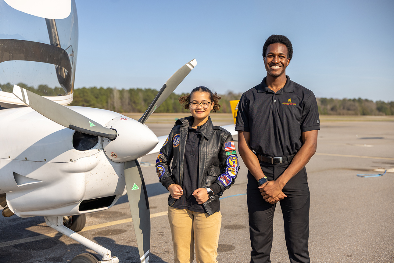 Students stand near airplane