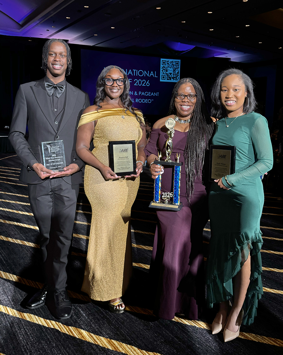 Two students and two alumni holding trophy and awards
