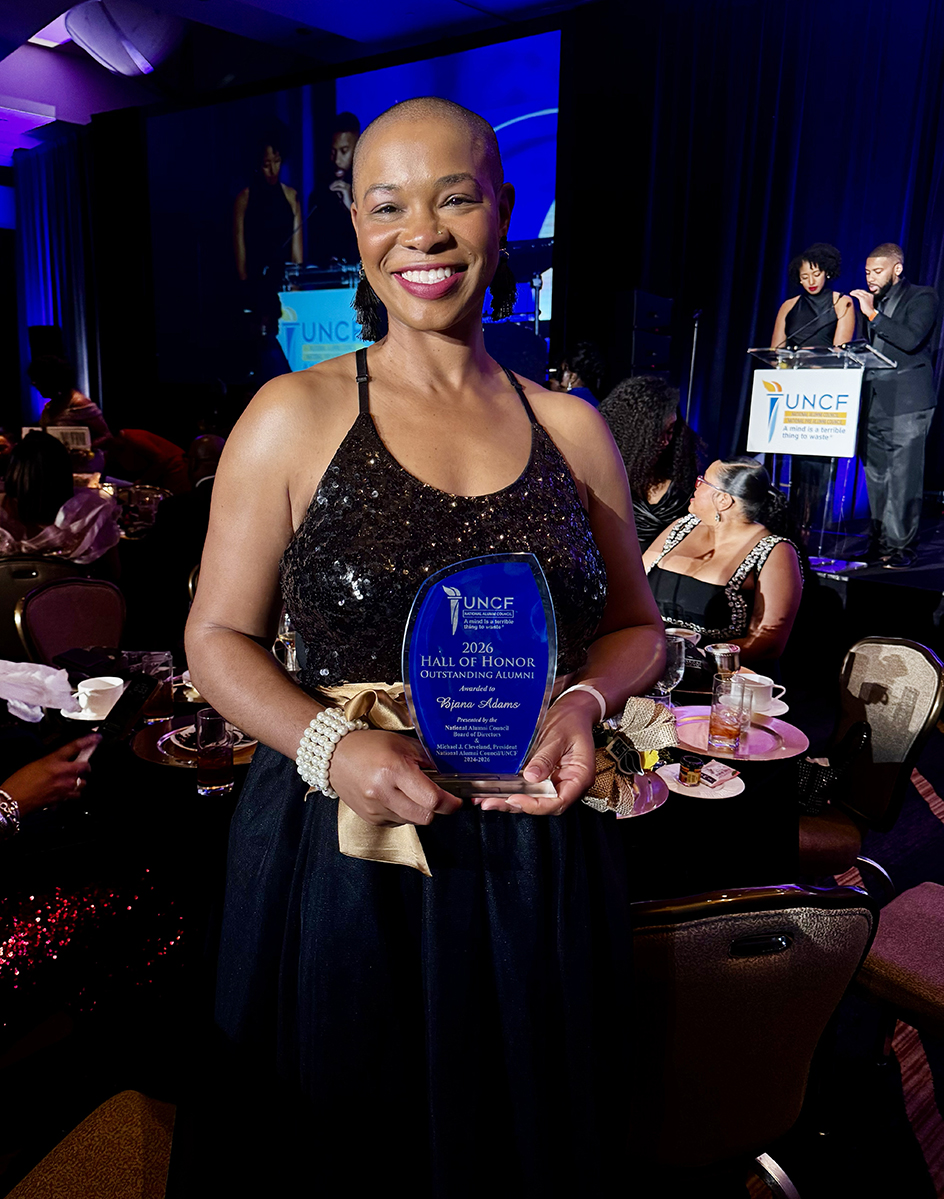 Female holding outstanding alumni award
