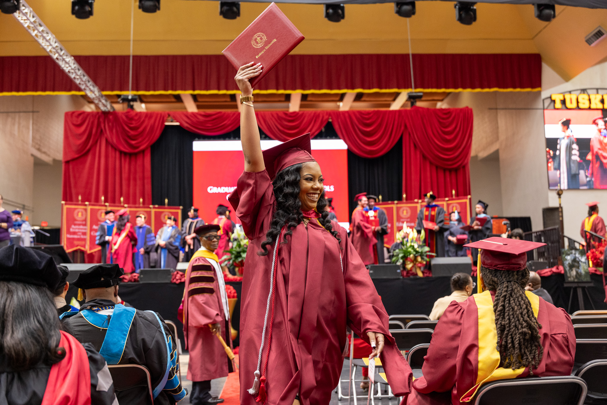 2026 Grad Commencement student raises diploma