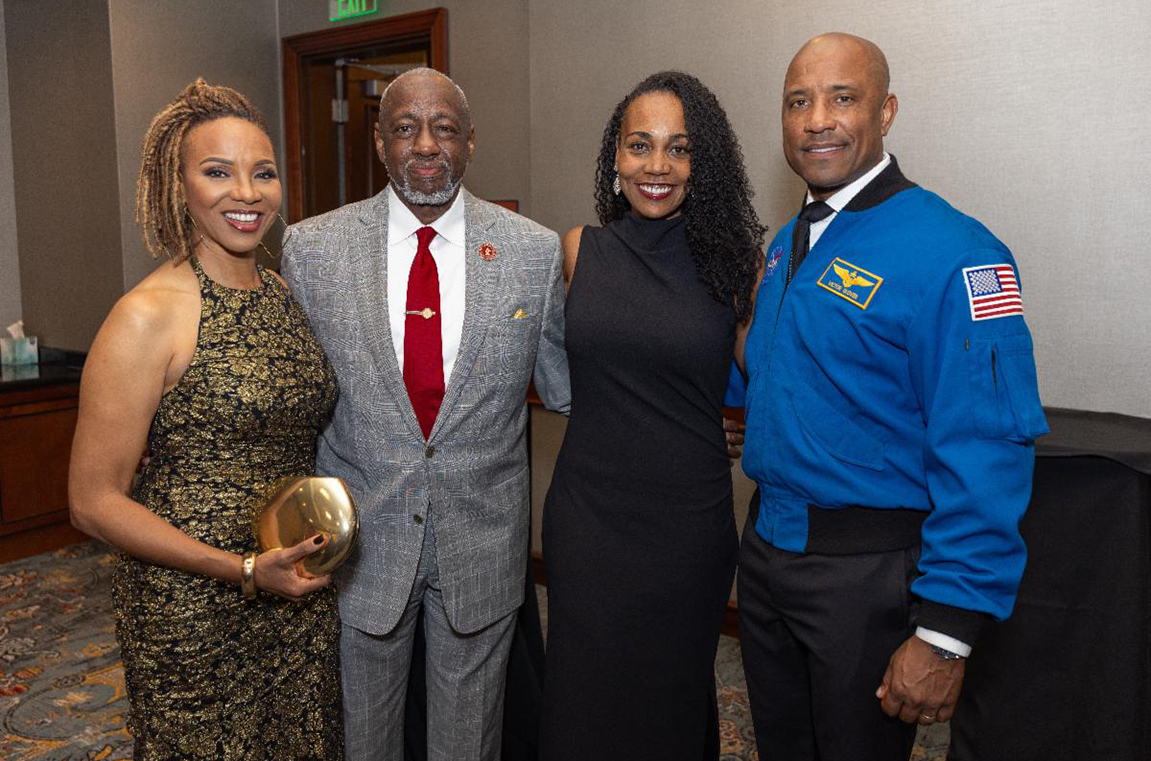 MC Lyte and Dr. Mark A. Brown standing with NASA astronaut Capt. Victor Glover and his wife