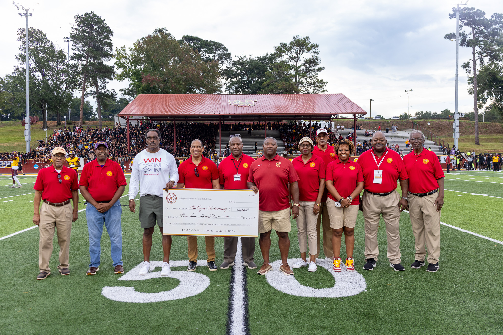 Picture of 11 Hall of Fame inductees standing on the field holding a check